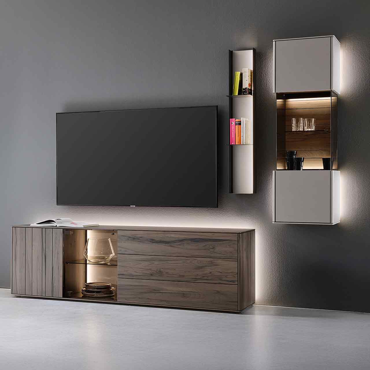Hartmann AUDRA 5610 - Wohnwand Nr. V36 - dreiteilig aus Altholzbuche Uyaa und Lack Sand Moderne dreiteilige Wohnwand bestehend aus einem Lowboard aus dunkelbraunem Holz mit Maserung und Glasausschnitt, einem Metallregal mit beleuchteter Lackfront und Metallböden und einer Hängevitrine in Lack sand - an dunkelgrauer Wand.