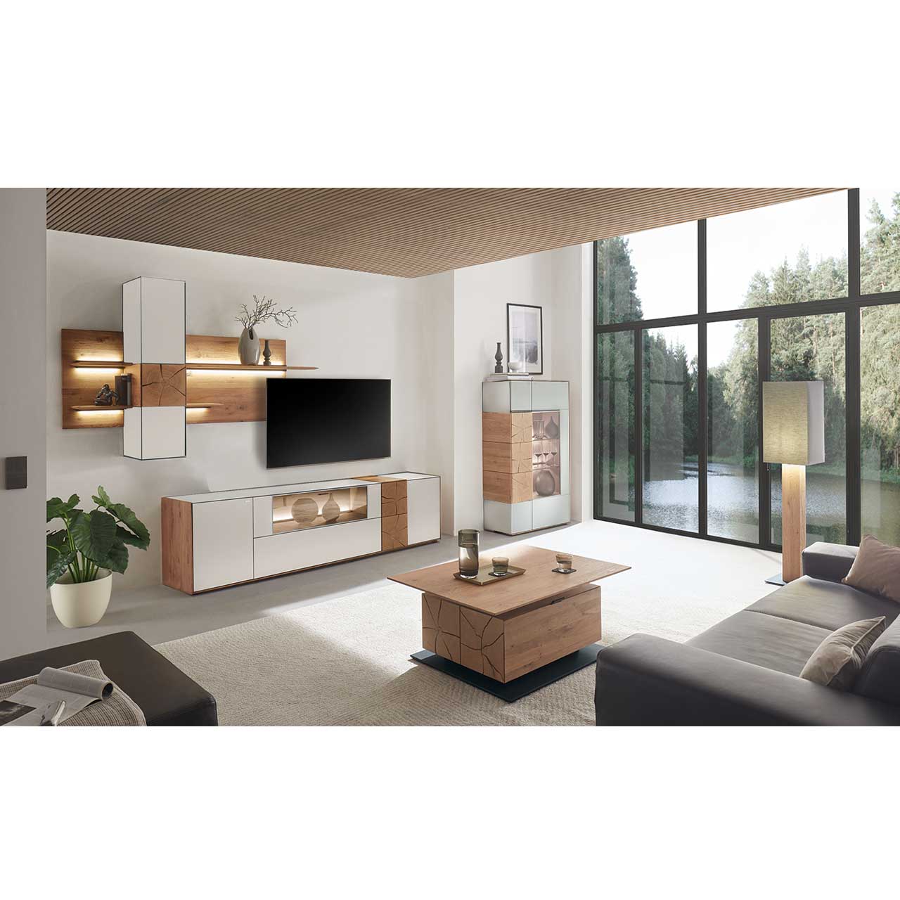 Wohnzimmer mit moderner Massivholz Wohnwand mit Mattglas weiß Fronten, mit Lowboard mit Glasausschnitt sowie Wandpaneel mit Regalböden und Hängeschrank. Rechts passendes Highboard mit Glasfront und Hirnholzscheiben. Im Vordergrund Holz-Couchtisch. 
