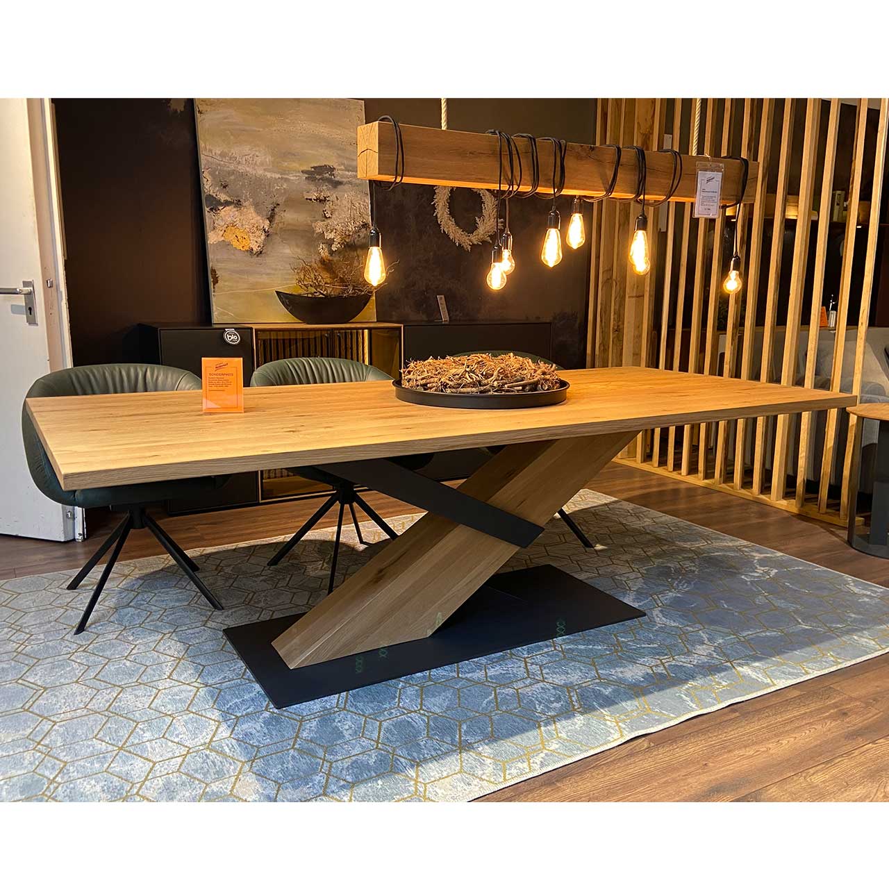 Hartmann SALE Möbel - NATURZEIT Esstisch Y100 8400E-1509 - Länge 240cm / Originalbild Ausstellung Moderner Esstisch aus massiver Kerneiche mit rechteckiger, gerader Tischplatte mit Hirnholz-Akzent. Träger ist ein schräg verlaufender Holzbalken, eingefasst von Metallstreben in Anthrazit. Die massive Bodenplatte besteht aus anthrazitfarbenem Baustahl.