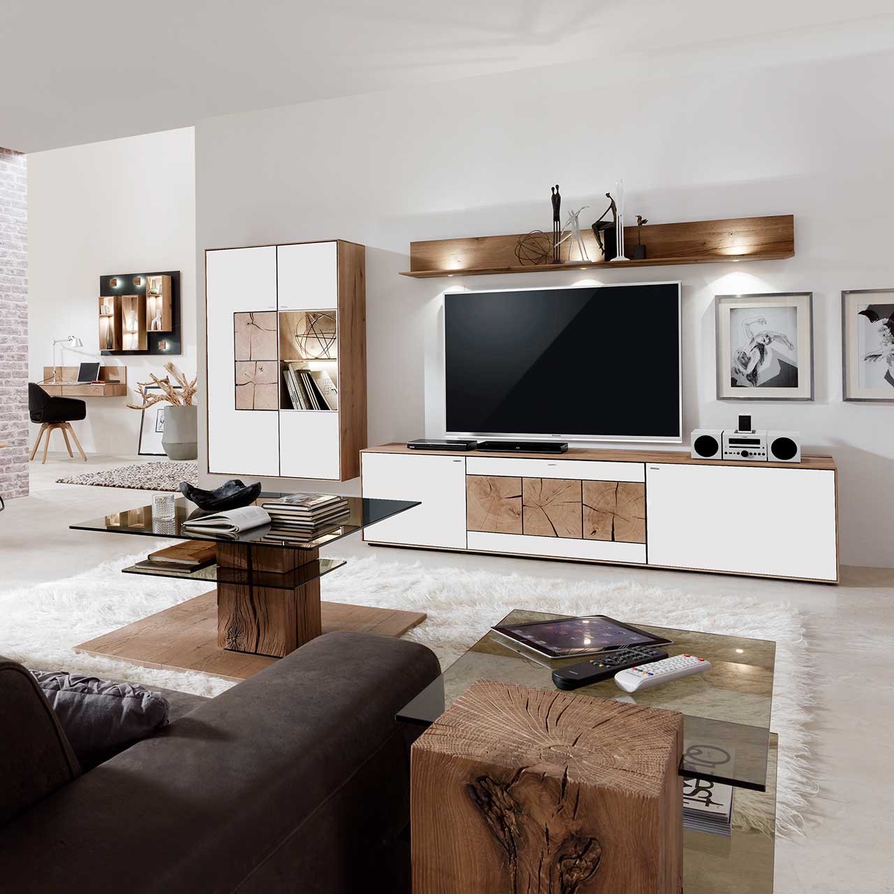 Wohnzimmer mit moderner dreiteiliger Massivholz Wohnwand mit Mattglas weiß Fronten und dekorativen Hirnholzscheiben: Lowboard mit Hirnholz, Wandregal mit Spotbeleuchtung, große Hängevitrine mit beleuchtetem Glasausschnitt und Hirnholz.