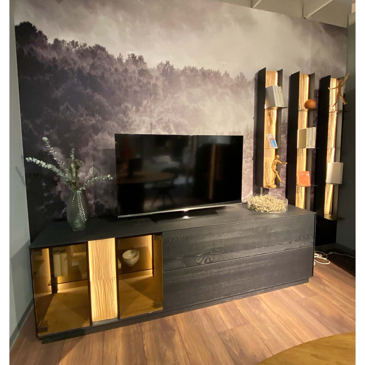 Hartmann SALE Möbel - KILVA Wohnwand 9160 Nr. V22 vierteilig - inkl. Beleuchtung / Originalbild Ausstellung Moderne vierteilige Massivholz Wohnwand aus anthrazitfarbener Kernesche und hellem Spaltholz: Lowboard mit Glasausschnitt, Klappe und Schubkasten und dekorativem Spaltholz, drei Metallregale mit Ablageböden und beleuchteter Spaltholzrückwand.