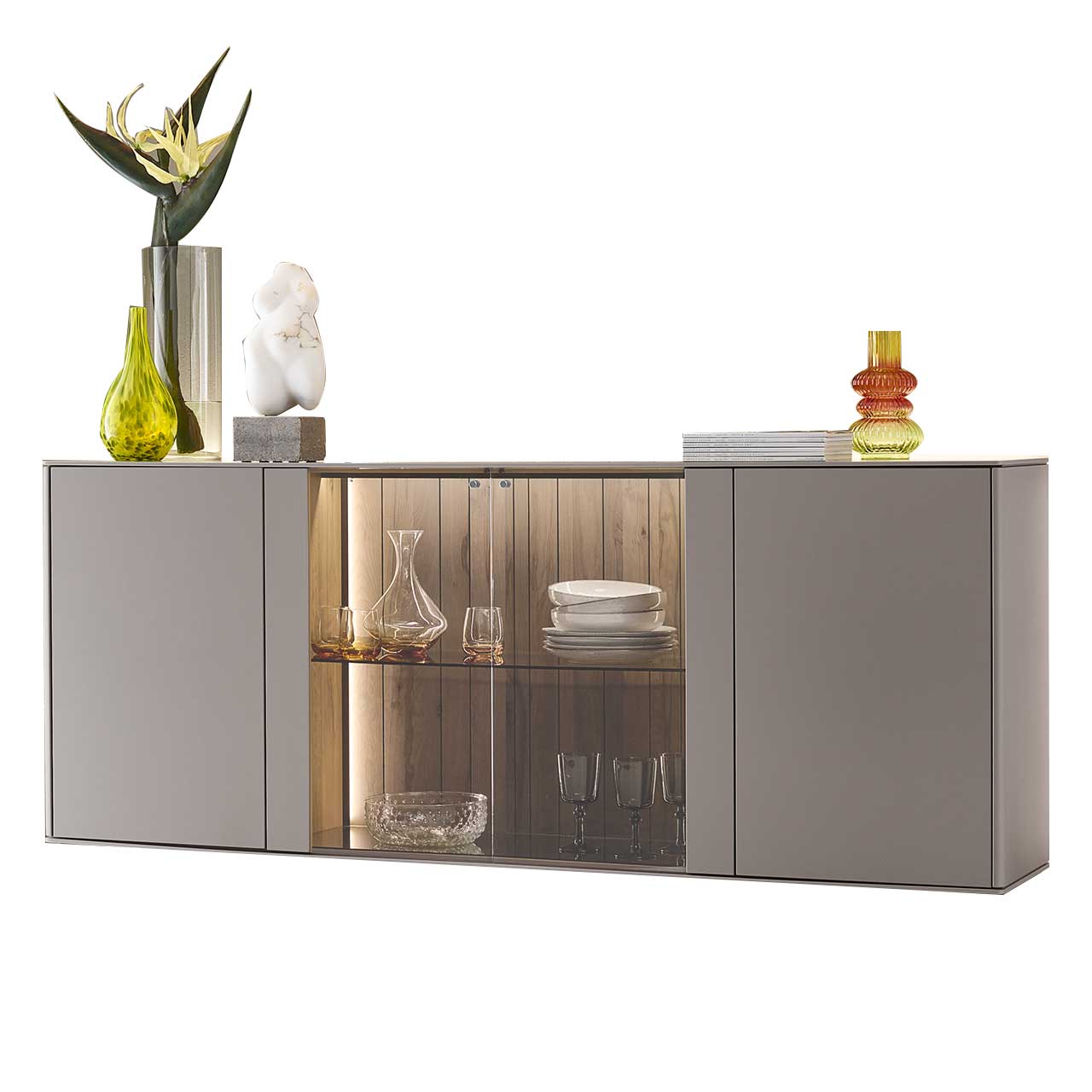 Modernes Sideboard aus Massivholz mit zwei Türen rechts und links lackiert in Sandfarben, mittig mit Glasausschnitt und einem Glasboden vor beleuchteter Holzrückwand in edler, dunkelbrauner Altholzbuche Uyaa.